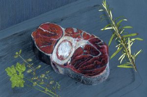 Ein Stück Fleisch auf einem Schneidebrett, daneben Küchenkräuter